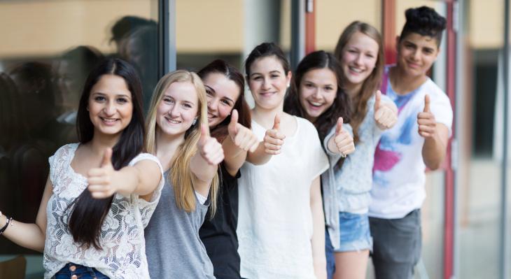 Gruppe junger Menschen, die in die Kamera schauen und den Daumen heben