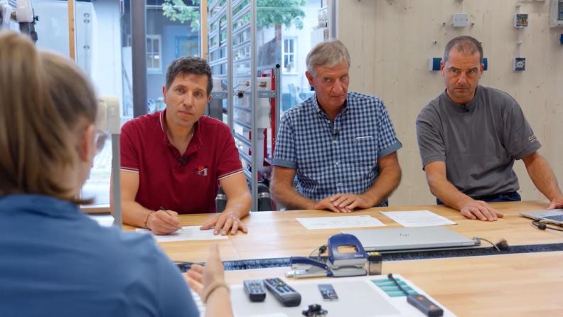 Drei Personen sitzen nebeneinander und schauen auf eine weitere Person, die gegenüber sitzt