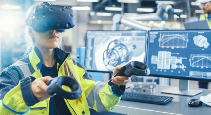 Frau in Arbeitskleidung mit VR-Brille vor PC-Bildschirmen