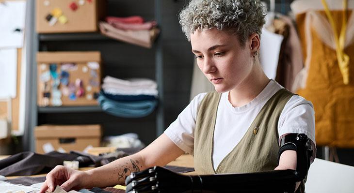 Frau mit Armprothese in Textilwerkstatt