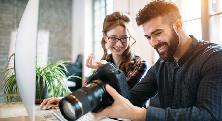 Fotografen blicken auf Kamera und lächeln dabei