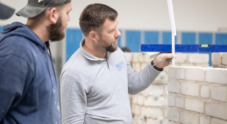 Zwei Männer vor im Bau befindlicher Wand